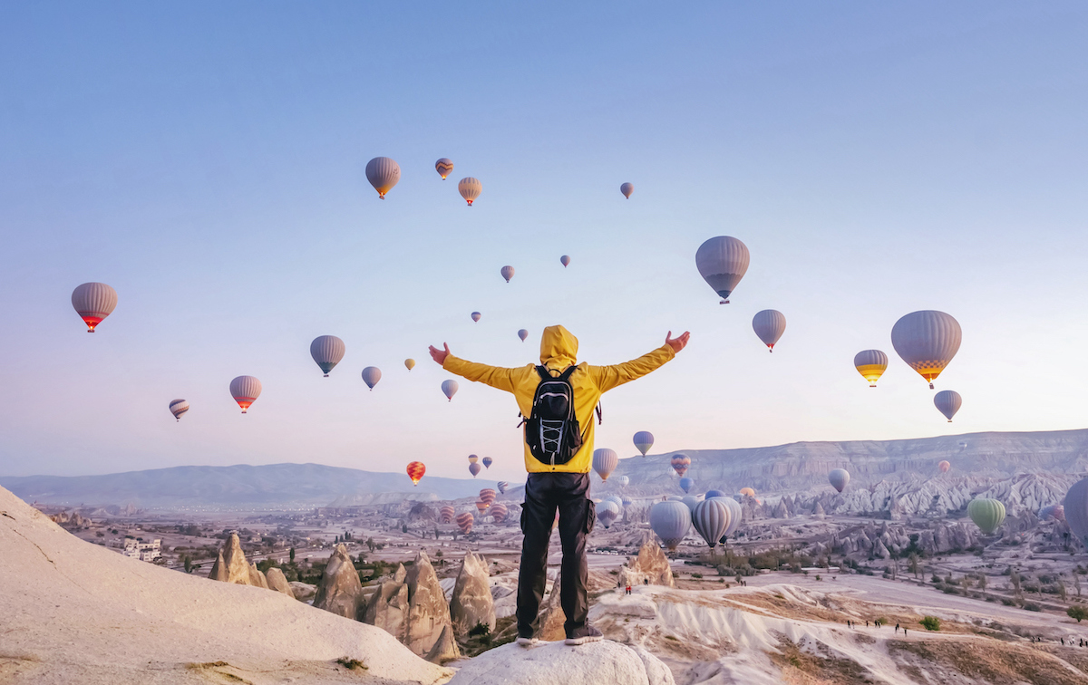 Man standing with his arms outstretched beholding a sky-full of hot air balloons as a metaphor for remotely supporting Logitech devices with GoTo Resolve