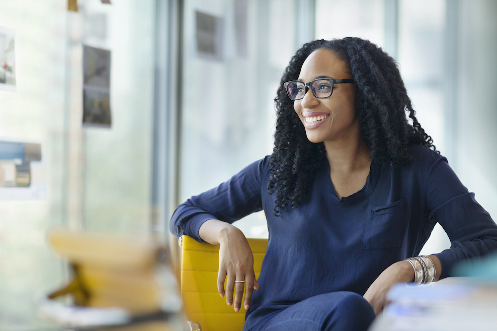 Woman smiling over her shoulder at work representing employee satisfaction, a key performance indicator IT teams should be tracking today